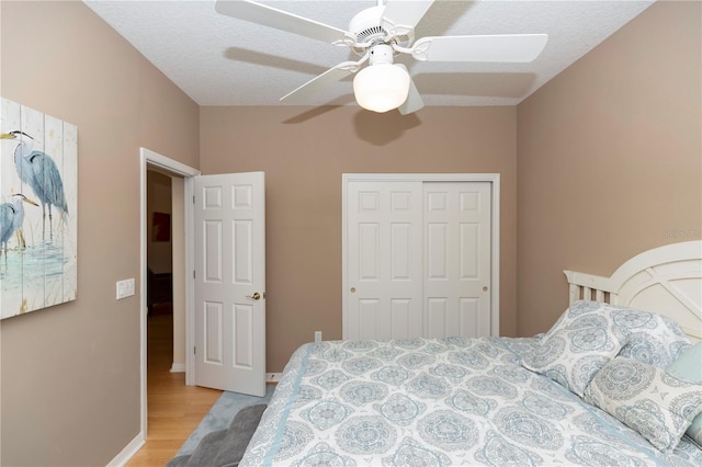 bedroom featuring a closet, a ceiling fan, light wood-style flooring, and baseboards