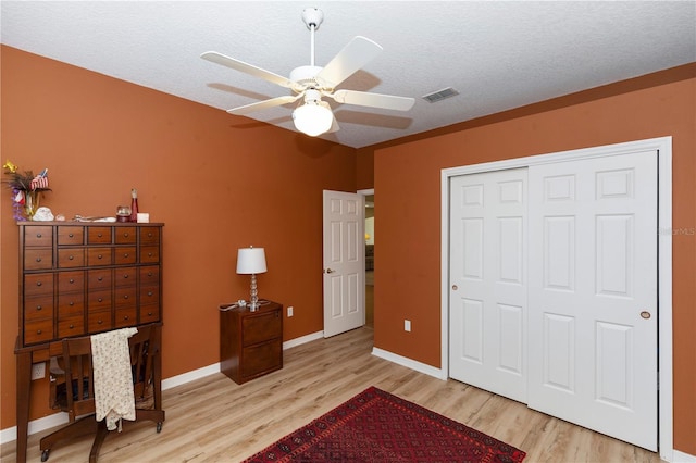 bedroom with ceiling fan, baseboards, wood finished floors, visible vents, and a closet