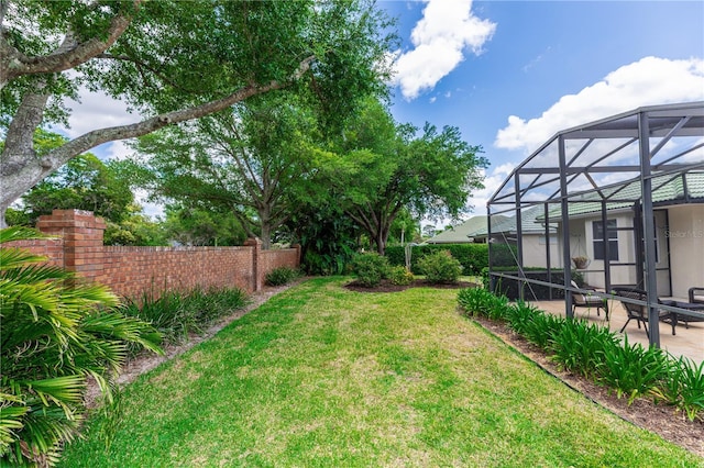 view of yard with glass enclosure, a patio, and fence
