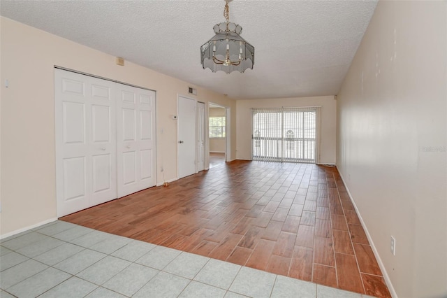 313 Dirksen Dr Unit B15, Debary, FL 32713 - unfurnished bedroom with a chandelier, wood finished floors, baseboards, a textured ceiling, and a closet