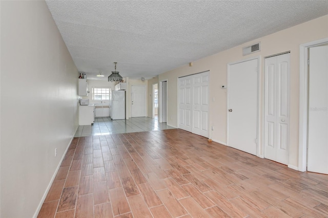 313 Dirksen Dr Unit B15, Debary, FL 32713 - unfurnished living room featuring light wood finished floors, a textured ceiling, and baseboards
