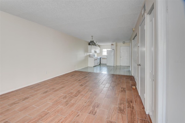 313 Dirksen Dr Unit B15, Debary, FL 32713 - spare room with light wood finished floors, a textured ceiling, a chandelier, and baseboards