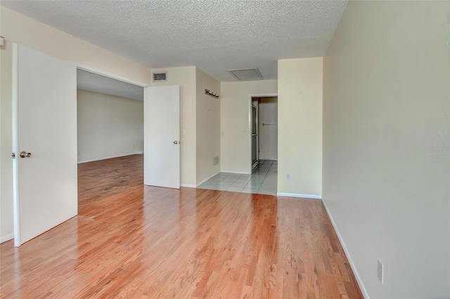 313 Dirksen Dr Unit B15, Debary, FL 32713 - empty room featuring light wood-style flooring, a textured ceiling, baseboards, and attic access