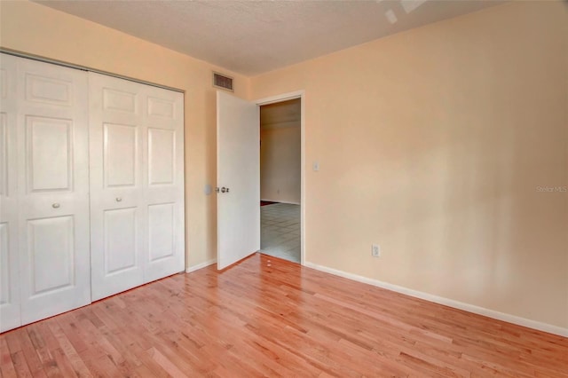 313 Dirksen Dr Unit B15, Debary, FL 32713 - unfurnished bedroom featuring light wood-type flooring, baseboards, a closet, and a textured ceiling