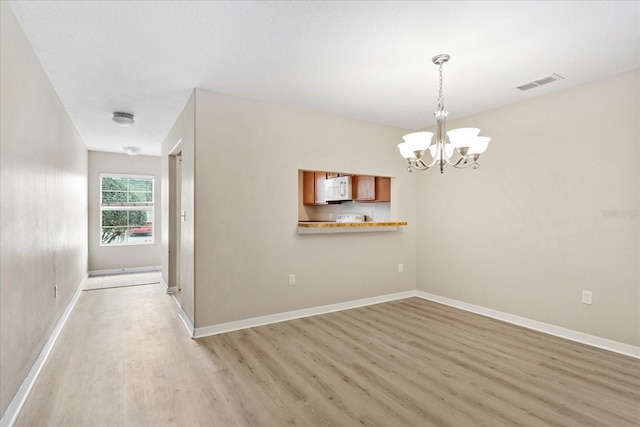 unfurnished room featuring light wood-style floors, baseboards, a notable chandelier, and visible vents