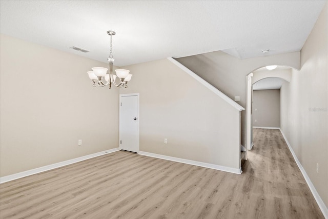 interior space with an inviting chandelier, visible vents, arched walkways, baseboards, and light wood-style floors
