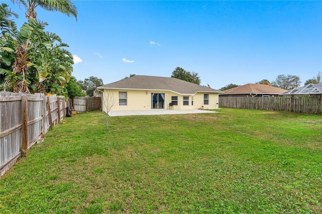 rear view of house featuring a fenced backyard, stucco siding, a lawn, and a patio area