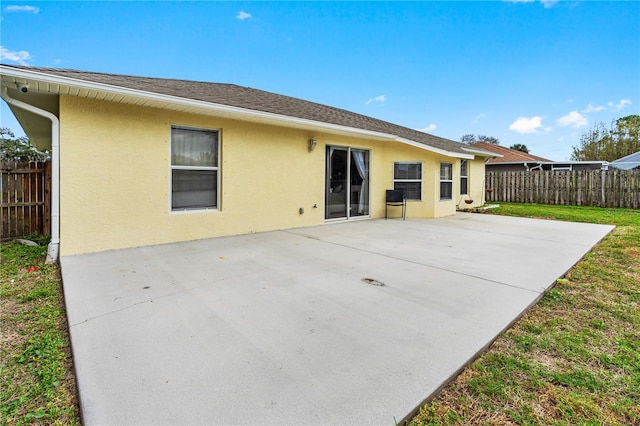 rear view of house with fence, a patio, and stucco siding