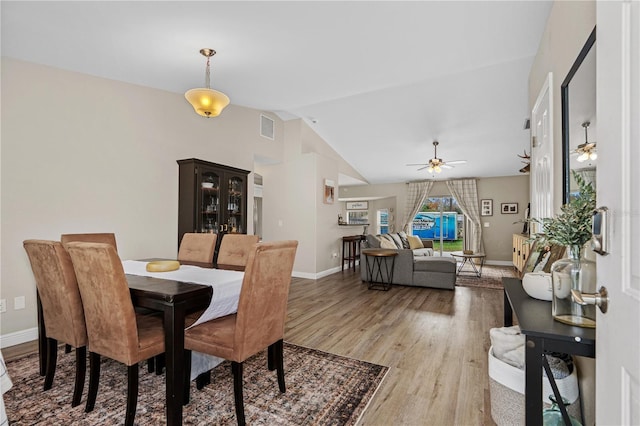 dining space with ceiling fan, visible vents, baseboards, lofted ceiling, and light wood-style flooring