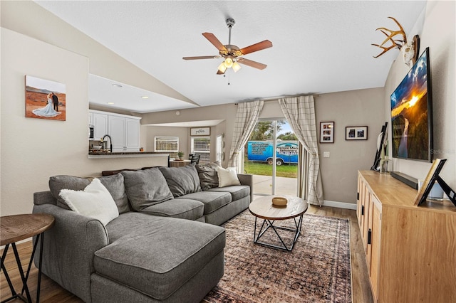 living room featuring baseboards, a ceiling fan, wood finished floors, and lofted ceiling