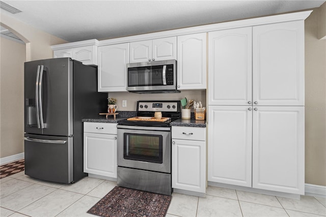 kitchen with visible vents, dark countertops, baseboards, white cabinets, and stainless steel appliances
