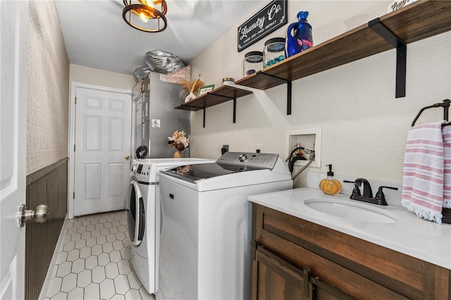 clothes washing area with washing machine and clothes dryer, light tile patterned floors, and a sink
