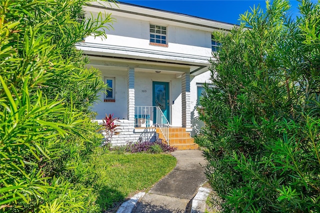 view of exterior entry featuring stucco siding and a porch