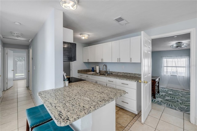 128 Oakridge Ave, Edgewater, FL 32132 - kitchen with visible vents, a sink, light stone counters, white cabinets, and light tile patterned flooring
