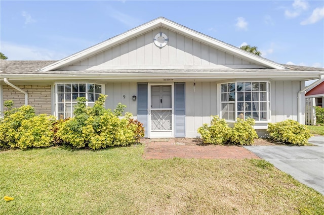 view of front of property featuring a shingled roof, board and batten siding, and a front yard