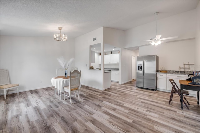 kitchen featuring stainless steel fridge, light wood-style flooring, ceiling fan with notable chandelier, and white cabinets