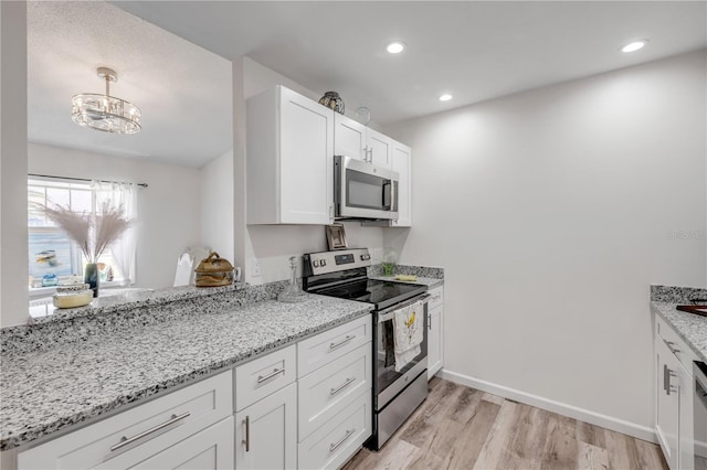 kitchen with light stone counters, light wood-style flooring, white cabinetry, and stainless steel appliances