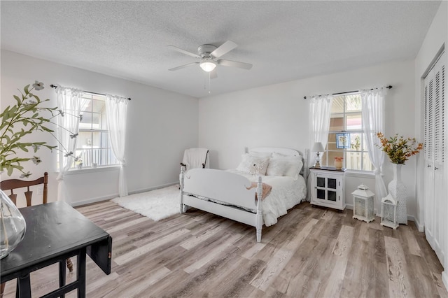 bedroom featuring a closet, a textured ceiling, light wood finished floors, and baseboards