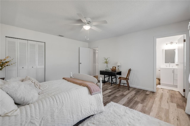 bedroom with a textured ceiling, visible vents, wood finished floors, a sink, and a closet