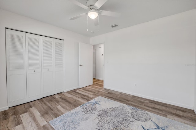 unfurnished bedroom with baseboards, wood finished floors, and visible vents