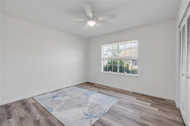 unfurnished bedroom with baseboards, a ceiling fan, a closet, and wood finished floors