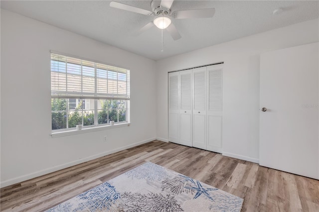 unfurnished bedroom with baseboards, ceiling fan, a closet, and wood finished floors