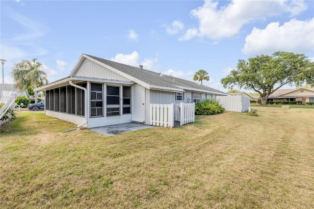 back of property featuring a yard, roof with shingles, fence, and a sunroom