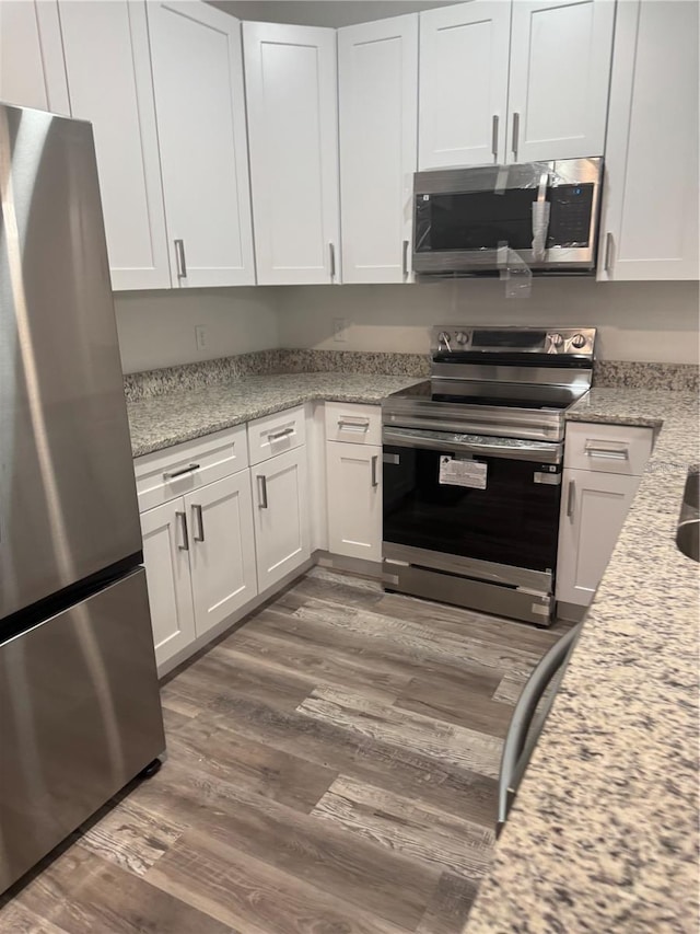 926 Clover St, Deland, FL 32720 - kitchen featuring wood finished floors, white cabinets, light stone countertops, and stainless steel appliances
