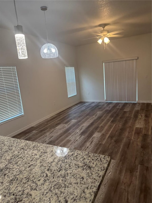 926 Clover St, Deland, FL 32720 - unfurnished living room featuring baseboards, ceiling fan with notable chandelier, and dark wood-style floors