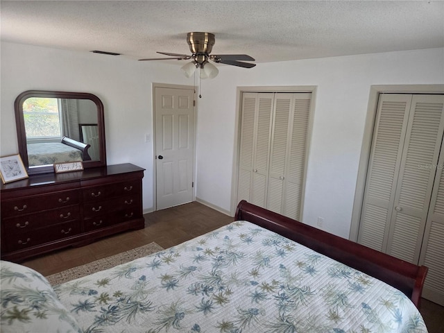 bedroom featuring two closets, a textured ceiling, ceiling fan, and wood finished floors