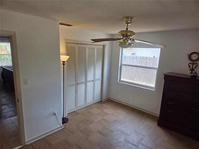 unfurnished bedroom with a textured ceiling, baseboards, ceiling fan, and a closet