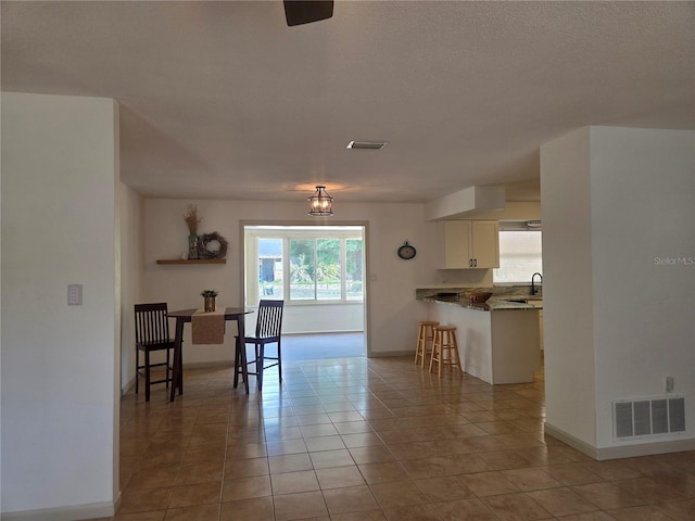 interior space with baseboards, visible vents, and light tile patterned floors