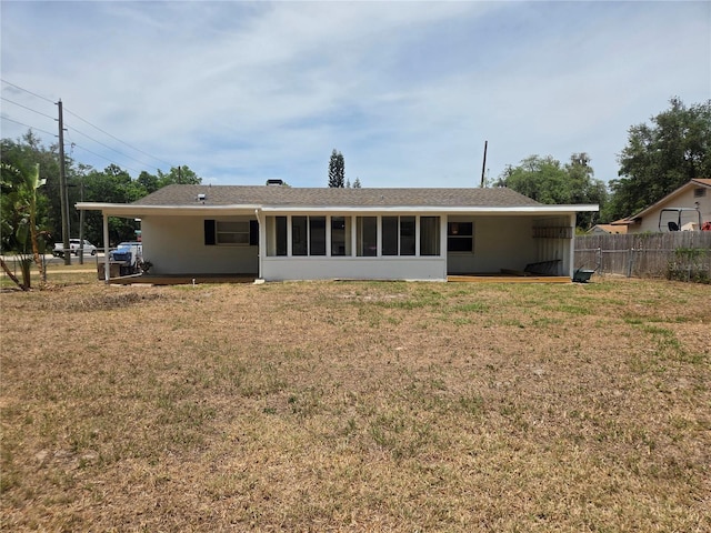 back of property with a sunroom, fence, and a yard