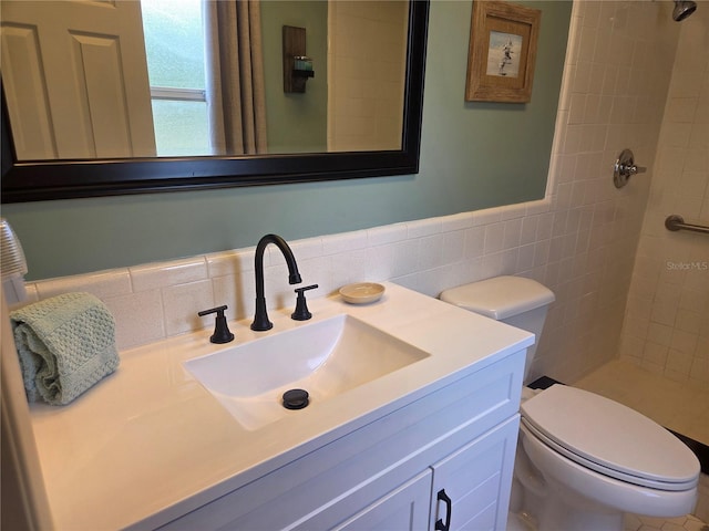 bathroom featuring vanity, a tile shower, toilet, and tile walls