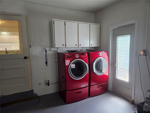 clothes washing area featuring cabinet space and washer and clothes dryer