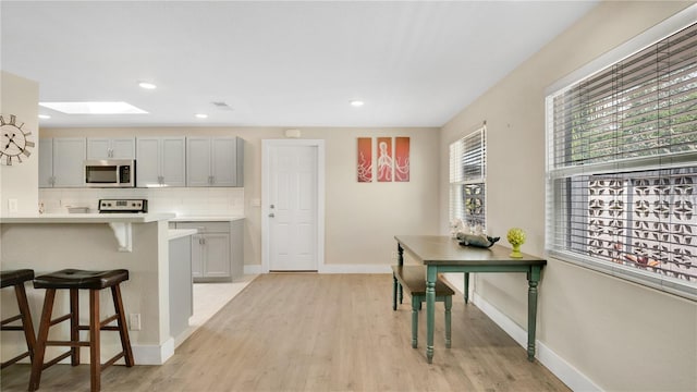 88 Valencia Dr, Ormond Beach, FL 32176 - kitchen with stainless steel appliances, a skylight, a kitchen bar, light countertops, and light wood-style floors