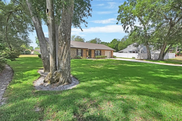 view of front of property featuring a garage, fence, a front lawn, and brick siding