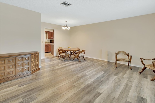 dining space with a notable chandelier, visible vents, baseboards, and light wood finished floors