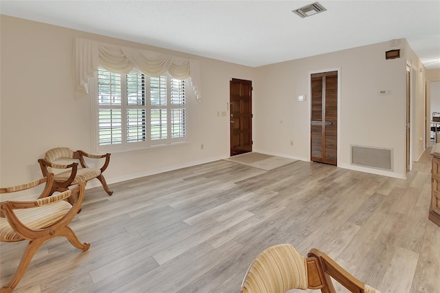 living area featuring baseboards, light wood finished floors, and visible vents