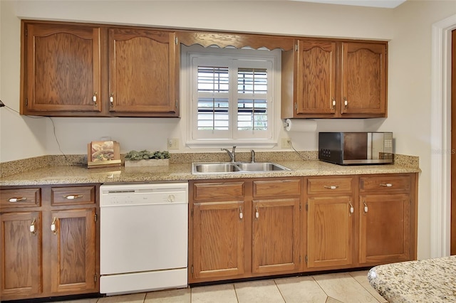 kitchen with a sink, light tile patterned flooring, dishwasher, and brown cabinets