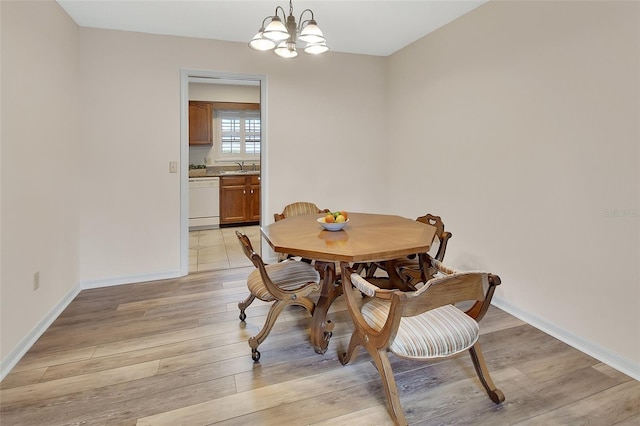 dining room featuring an inviting chandelier, baseboards, and light wood finished floors