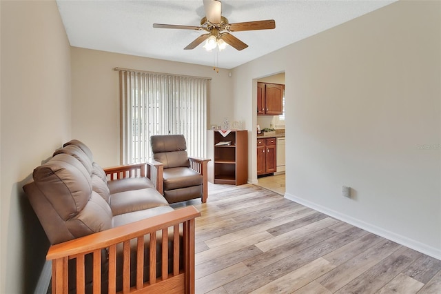 living area with baseboards, ceiling fan, light wood-type flooring, and a wealth of natural light