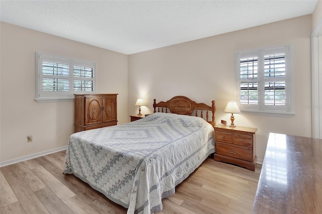 bedroom with baseboards, multiple windows, and light wood-style flooring