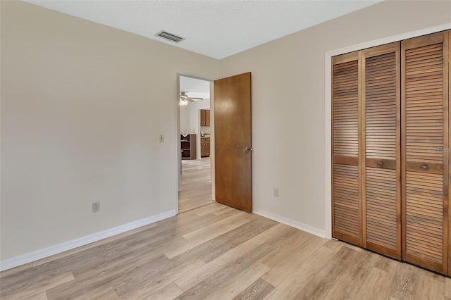 unfurnished bedroom with baseboards, a closet, light wood-type flooring, and visible vents