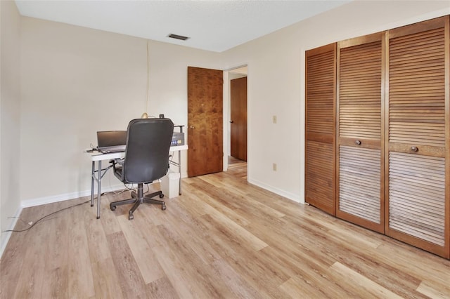 home office featuring visible vents, light wood-style flooring, and baseboards