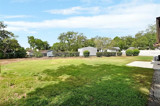 view of yard with a fenced backyard, a patio, an outdoor structure, and a shed