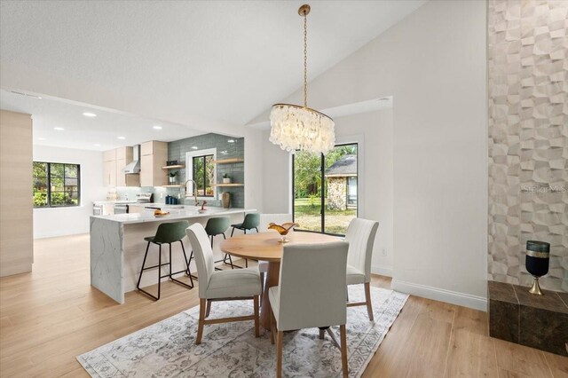 dining area with light wood-style floors, high vaulted ceiling, a chandelier, recessed lighting, and baseboards
