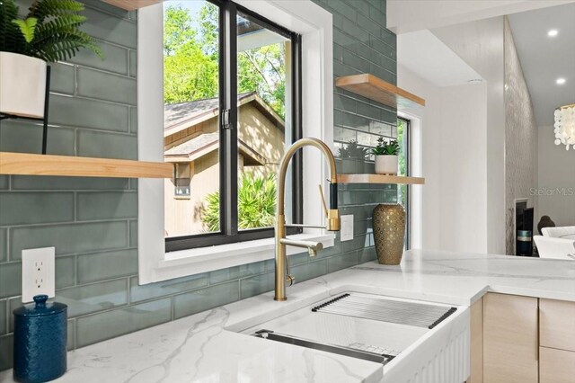 details featuring a chandelier, open shelves, light stone counters, and a sink