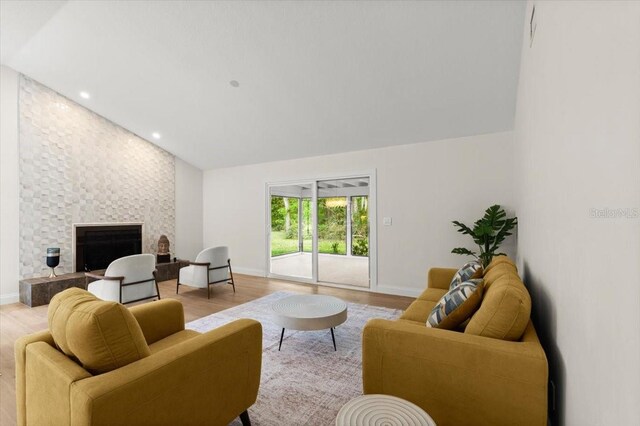 living room with baseboards, a fireplace, vaulted ceiling, and light wood-style flooring