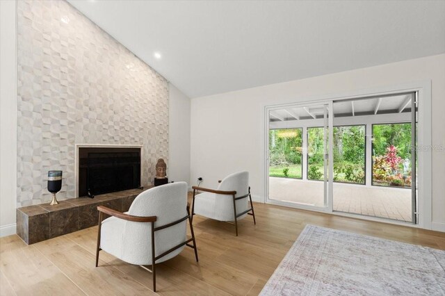 living area featuring a tile fireplace, wood finished floors, baseboards, lofted ceiling, and recessed lighting